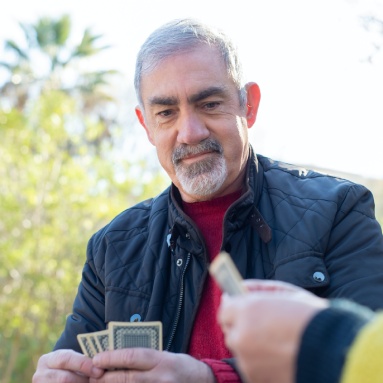 Sagora | Senior man playing a card game